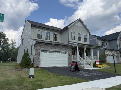 The Everly model home at Sadler Square in Glen Allen, VA, with gray James Hardie siding, stone veneer, and a covered front porch