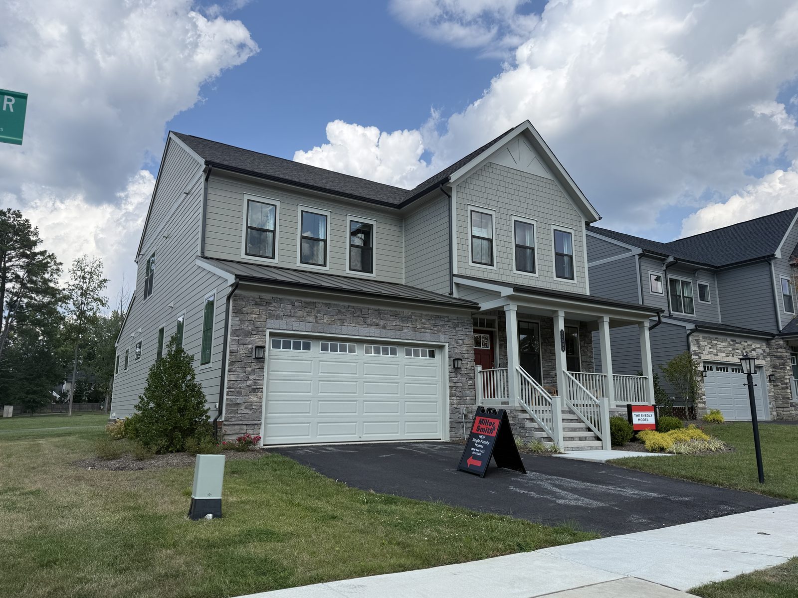 The Everly model home at Sadler Square in Glen Allen, VA, with gray James Hardie siding, stone veneer, and a covered front porch